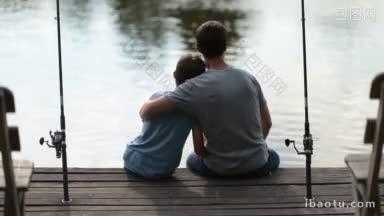 <strong>背影</strong>关怀父亲拥抱他的儿子，坐在木码头湖边钓鱼在夏天深情